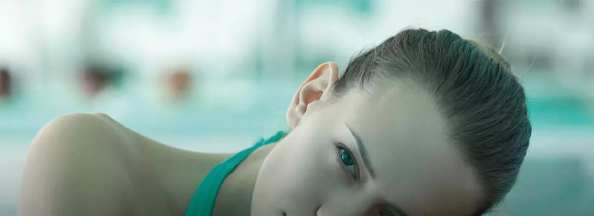 Donna in piscina, rilassata con testa appoggiata sul bordo.