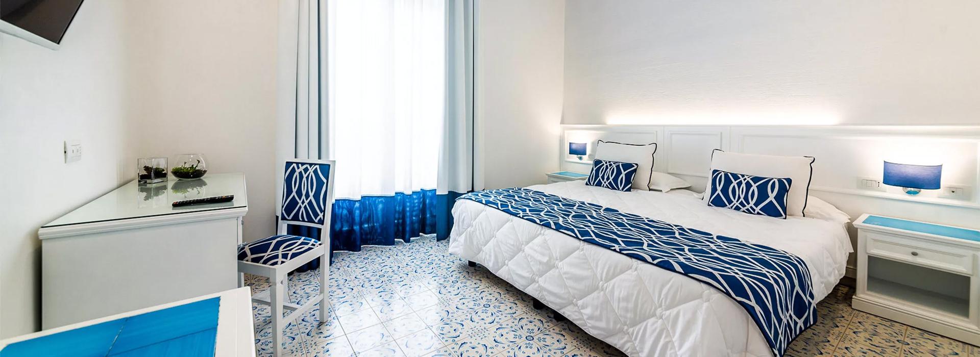 Camera moderna con decorazioni blu e bianche, pavimento piastrellato e arredi eleganti.