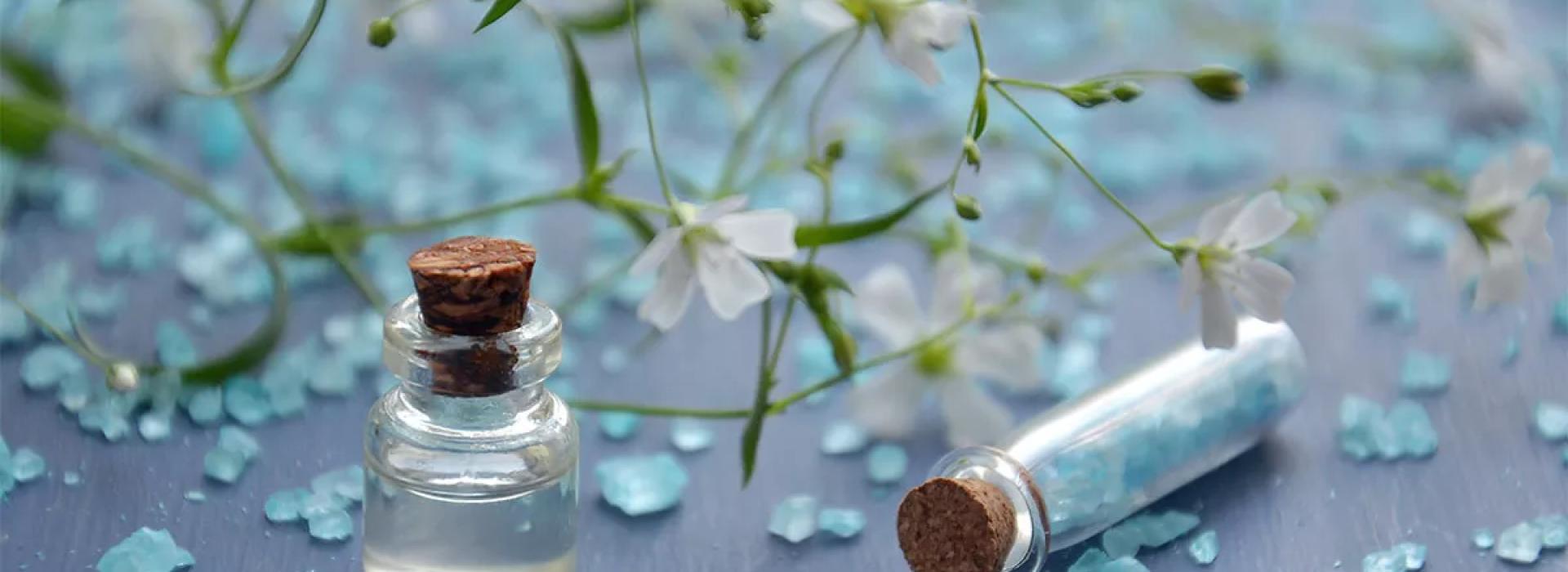 Fiori bianchi, cristalli blu e flaconi di vetro su sfondo blu.