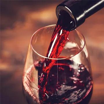 Vino rosso versato in un calice, creando un'atmosfera calda e accogliente.