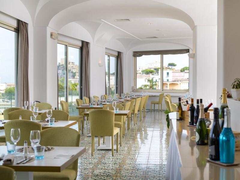Elegant restaurant with panoramic views, modern decor, and displayed wine bottles.