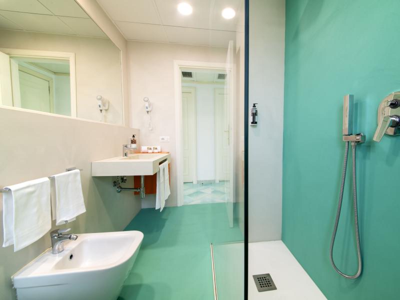 Modern bathroom with shower, bidet, and aqua green walls.