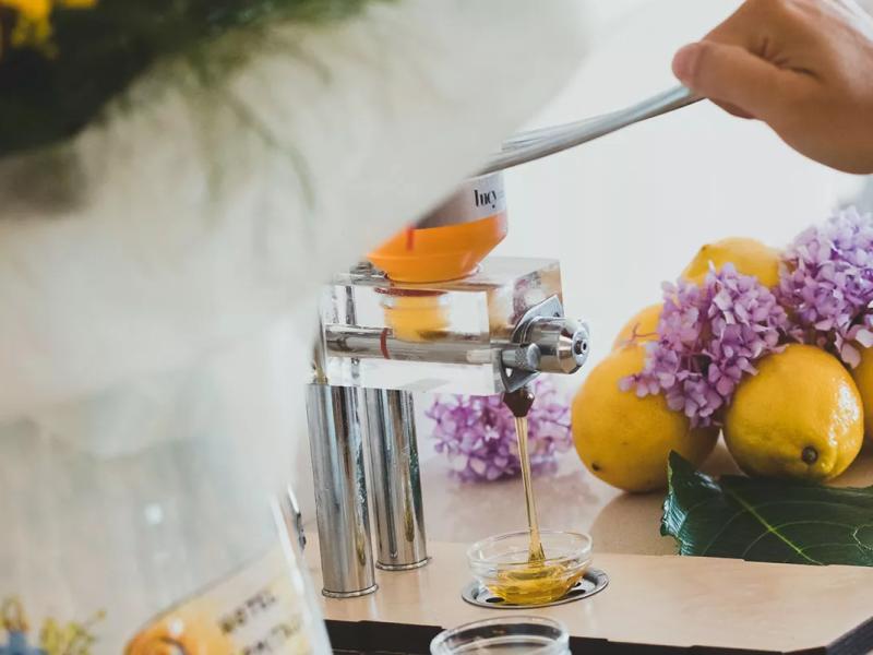 Estrattore di miele con limoni e fiori lilla sullo sfondo.