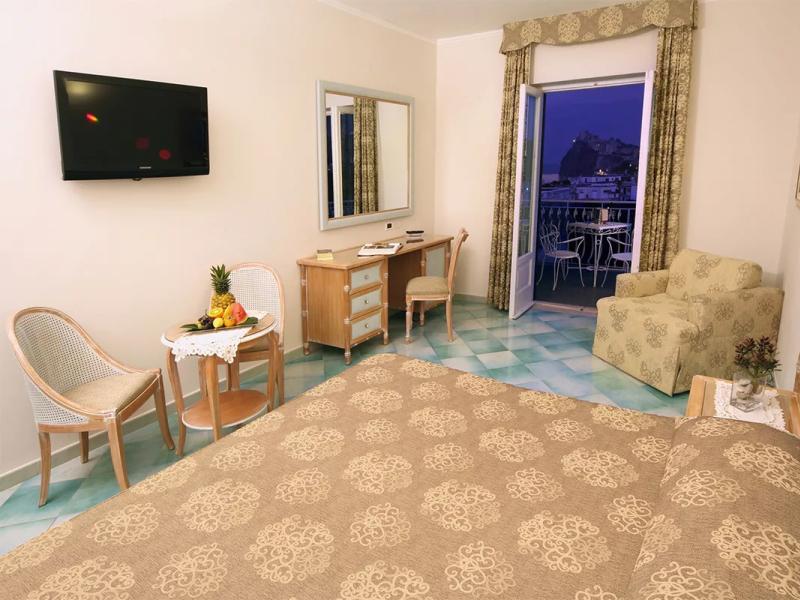 Camera d'albergo con vista, arredi classici e balcone, decorata con motivi beige.
