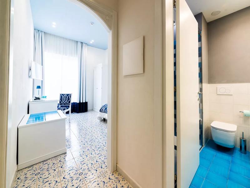 Camera luminosa con bagno privato, pavimenti decorati in blu e bianco.