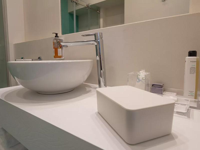 Bagno moderno con lavabo, dispenser sapone e prodotti per la cura personale.