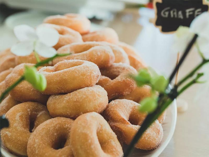 Un piatto di graffe zuccherate, dolci tipici italiani, con fiori decorativi.