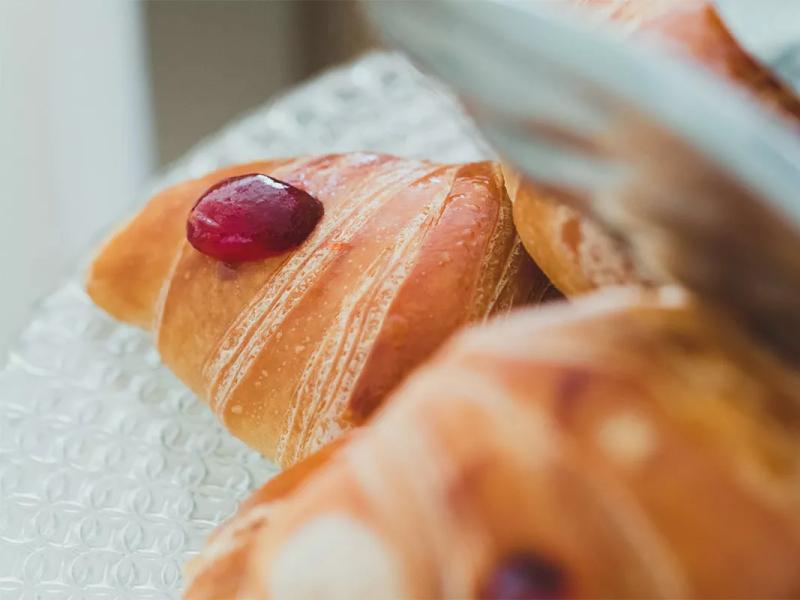 Croissant con marmellata su piatto di vetro, dettagliato e invitante.