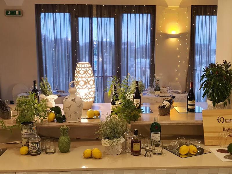 Bar elegante con piante aromatiche, bottiglie di vino e decorazioni luminose.